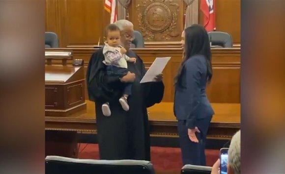 قاض يحمل رضيعا بينما تؤدي والدته